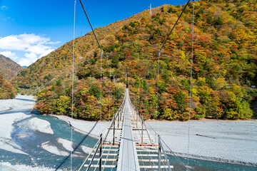 紅葉に染まる山々の中にたたずむ吊り橋