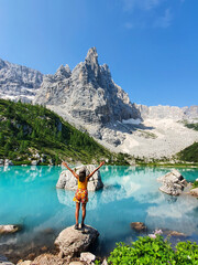 Joyful traveler enjoying the turquoise lake surrounded by mountains Lago Di Sorapis Dolomites Italy