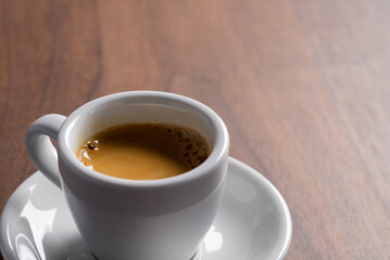 Fresh espresso in a white cup on walnut table with copy space