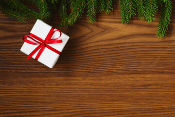 Chrismtas background top view with fir branches on wood background with present box