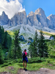 Fototapeta premium A peaceful hiker gazes up at majestic mountain peaks in the Dolomites during a sunny afternoon