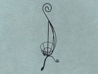 The picture shows a small hanging plant stand made from The black aluminum frame has a stand and a...
