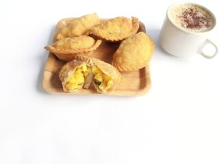 Pastel cake, a traditional Indonesian snack. Served on a woven bamboo wooden plate and a cup of black coffee. On a white background