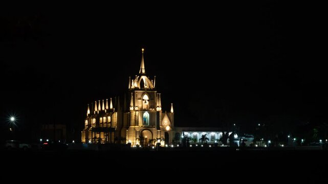 4K Timelapse footage of the Neo-Gothic Mae de Deus Catholic church in Saligao Goa at dusk night with traffic light trails and illuminated church and people visiting the church