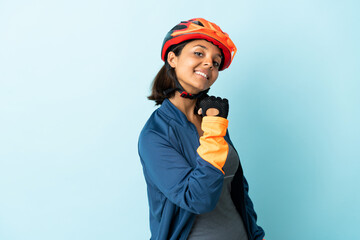 Young cyclist woman isolated on blue background proud and self-satisfied