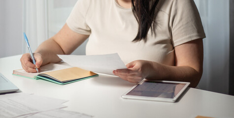 Female paying bills at home. Woman holding invoice in hands and calculates amount of debt. Bill payment online concept.
