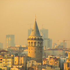 Galata Tower illuminated by sunset hues, framed by Istanbul's evolving skyline