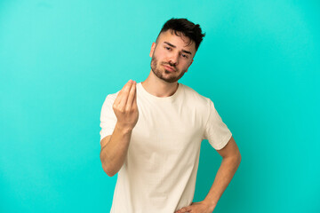Fototapeta premium Young caucasian man isolated on blue background making Italian gesture