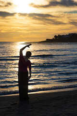 Fototapeta premium Woman practicing yoga on the beach at sunset