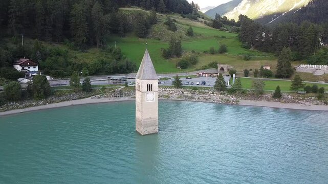 The iconic old church Tower of Graun emerging from the water of the artificial lake of Reschensee in Curon Venosta, South Tyrol, Italy