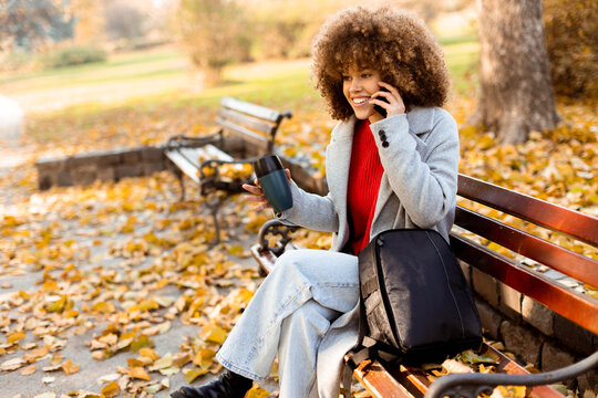 Enjoying a lively conversation while savoring coffee in a picturesque autumn park with colorful leaves