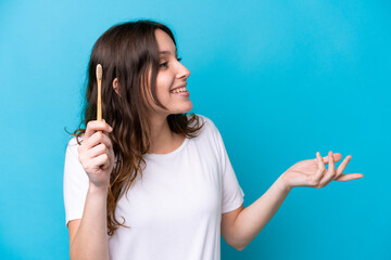 Obraz premium Young caucasian woman brushing teeth isolated on blue background with surprise facial expression