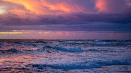 Obraz premium A breathtaking sunset casts vibrant hues over rolling ocean waves, creating a serene and colorful seascape full of rich purples and pinks.