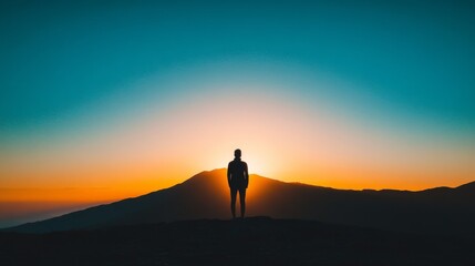 Person Standing Against a Beautiful Sunset Behind a Mountain Landscape