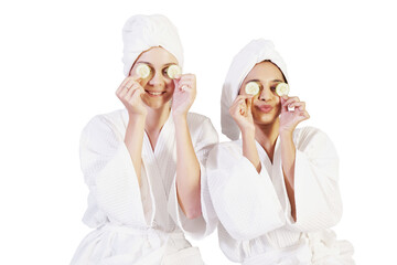 Smiling Caucasian and Asian couple girls friends wearing bathrobe and holding sliced ​​cucumber for facial eyes skin and face care together for spa treatment clip art and element