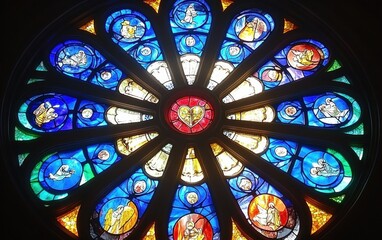 Beautiful Circular Stained Glass Window Featuring Colorful Biblical Scenes and Intricate Designs in a Historic Church Setting