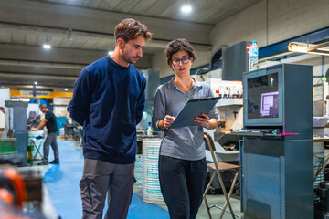 Manager and engineer doing paperwork standing and talking at factory