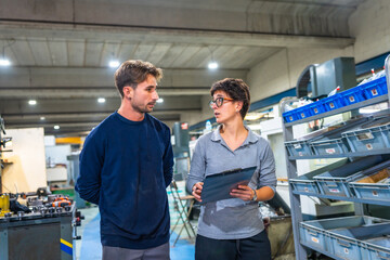 Naklejka premium Engineer and manual worker talking while doing inventory at factory