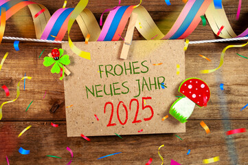 Wooden hang tag and slate with four leaf clover and sparklers with happy new year 2025 on wooden weathered background