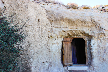 Ancient cave dwelling with wooden door carved into white rock face showing historical human habitation