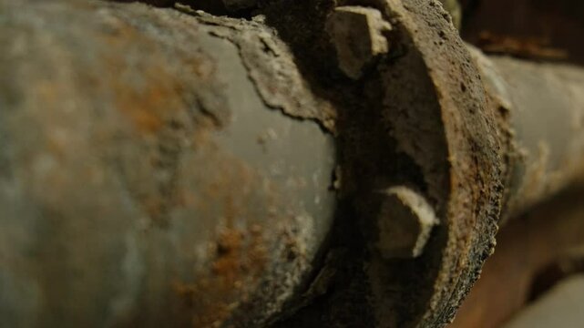 Detailed view of corroded industrial metal pipes with rust, flaking layers, and weathered bolts, capturing the texture of decay and neglect in an industrial setting.