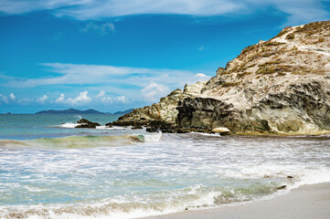 A rocky shoreline with a blue sky and ocean waves