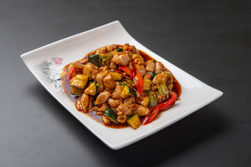 Kung pao chicken with peanuts  on a plate up close isolated on dark background, traditional Chinese cuisine