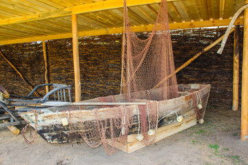 Old wooden fishing boat with nets under rustic shelter roof showing traditional maritime equipment...