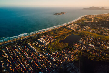 Fototapeta premium Coastline with ocean and town with sunset tones in Florianopolis