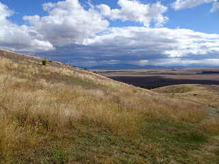 view above mount John summit near lake Tekapo, New Zealand, South island. Landscape with meadows and grass land and storm clouds. 