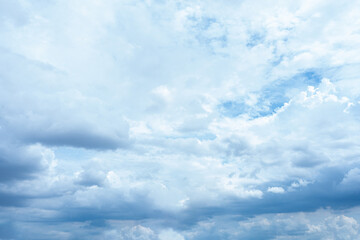 Fluffy white clouds drift across a bright blue summer sky