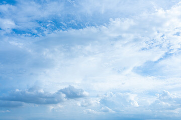 Fluffy cumulus clouds drift across a bright blue summer sky