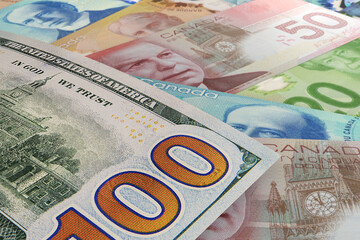 Back of US $100 bill with Canadian dollar banknotes in the background. Foreign exchange market....