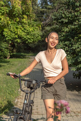 Obraz premium Beautiful laughing Asian girl with bicycle in city park