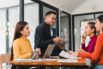 Collaborative business meeting with diverse professionals discussing strategies. team engages with charts and digital devices, showcasing teamwork and innovation