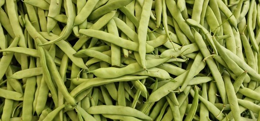 green flat beans laid out in a pile for sale in a vegetable market