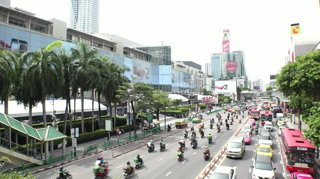 BANGKOK, THAILAND - AUGUST 2024 : High angle view of busy traffic around downtown shopping area in daytime. Transportation and street traffic concept video.
