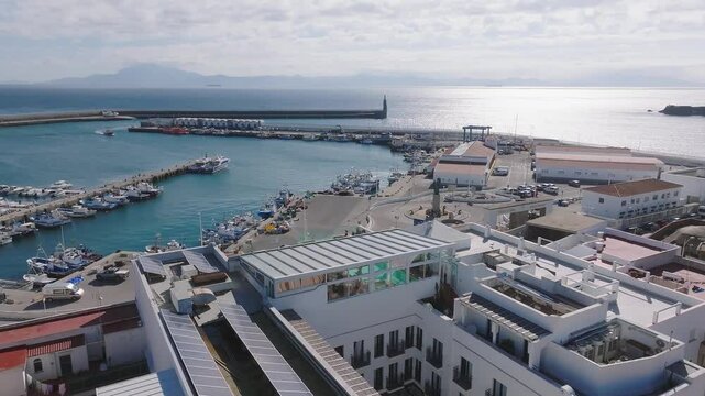 Aerial view of Tarifa with Castillo de Guzman, vibrant marina, and Punta de Tarifa lighthouse. Strait of Gibraltar and Morocco visible in the distance.