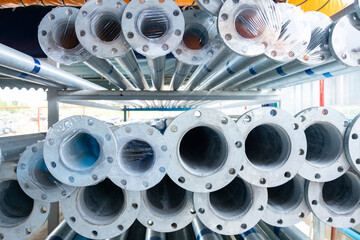 Stacked steel pipes with flanges in storage area 