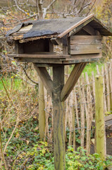 Old wooden birdhouse standing on a post in a garden