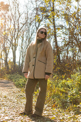 Seasonal autumn fashion. Modern young woman wearing fashionable warm clothes posing in the autumn park.