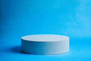 White rounded podium on a bright blue background. Minimalistic photo style.