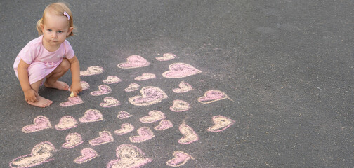 Fototapeta premium child draws a heart on the asphalt with chalk. Selective focus
