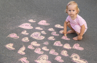 Fototapeta premium child draws a heart on the asphalt with chalk. Selective focus