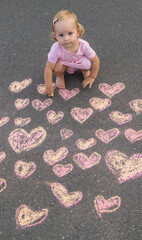 Naklejka premium child draws a heart on the asphalt with chalk. Selective focus