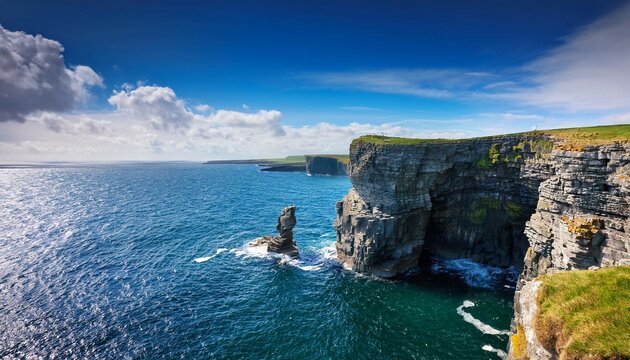 rough stone cliff and dun briste sea stack blue ocean water and blue cloudy sky nature scene in downpatrick head ireland popular travel and tourism landmark area