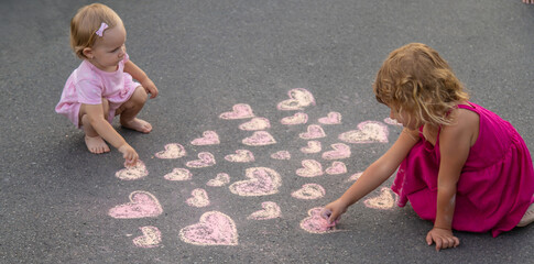Fototapeta premium child draws a heart on the asphalt with chalk. Selective focus