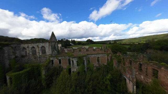 Drone FPV of historic ruins of Aulne Abbey Monastery surrounded by greenery in Thuin, Liege, Belgium