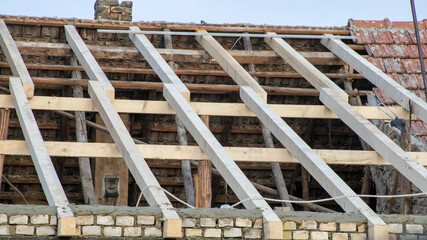 A partially repaired roof showing exposed wooden beams highlights ongoing renovation work and...