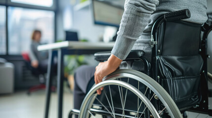 Obraz premium Woman in a wheelchair next to an office desk; hand close-up, unrecognizable person.